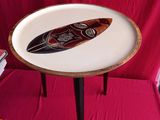 une petite table recouverte d'une nappe rouge, sur laquelle est posée une planche de surf