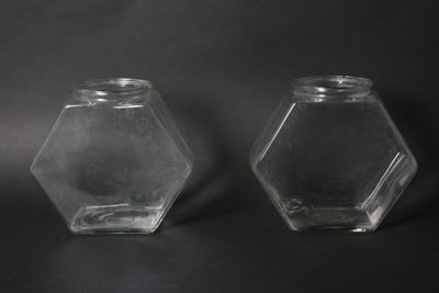 two clear glass hexagonal jars on a black background