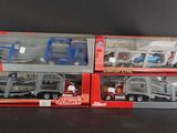 Trois camions miniatures dans leur emballage sont alignés sur une surface noire