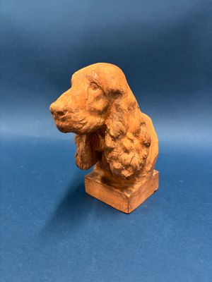 une vieille statue représentant un chien assis sur un bloc de bois