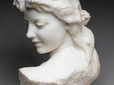 a white sculpture of a woman ' s head with a flower in her hair