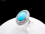 a close up of a ring with a turquoise stone surrounded by diamonds