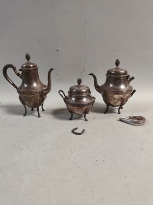 trois théières en argent et une cuillère posées sur une table
