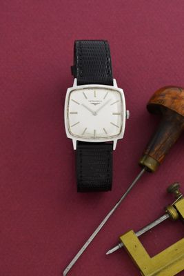 une montre posée sur une table à côté d'une paire d'outils