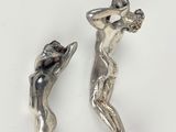 two silver figurines of a woman and a man holding a flower