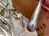 a person holding a spoon with a lot of silver spoons on it