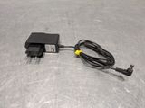 an ac adapter plugged to a power cord on a metal surface