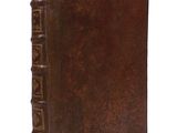 an old book with a brown cover sitting on top of a white surface