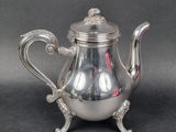 a silver tea pot with a handle on a table