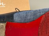 pair of red and black shoes sitting on top of a pair of blue jeans