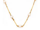 un collier en or avec des perles et une chaîne sur fond blanc