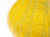 a yellow vase sitting on a table with a white background