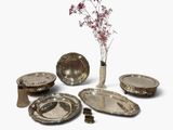 a vase with a flower in it next to a bunch of silver plates