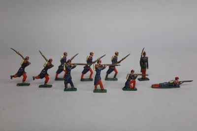 Plusieurs figurines de petits soldats sont disposées sur une surface blanche