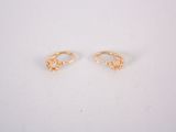 une paire de boucles d'oreilles en or sur une surface blanche