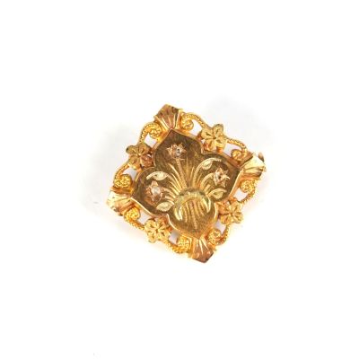 une image représentant une broche plaquée or ornée de fleurs et de feuilles