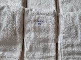 Quatre serviettes blanches sont alignées sur un lit recouvert d'un drap blanc