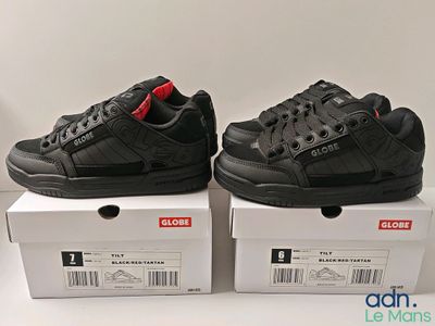 deux boîtes de chaussures noires posées l'une sur l'autre sur une surface blanche