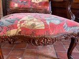 a red chair with a colorful upholstered seat on a brick floor