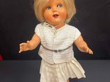 doll with blonde hair and blue eyes wearing a white shirt and skirt