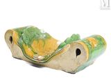 un vase vert et jaune posé sur une surface blanche