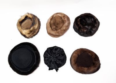 Plusieurs chapeaux différents sont alignés sur une surface blanche