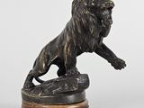 statue en bronze représentant un lion, posée sur un socle en bois, sur fond blanc