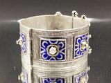 un gros plan sur un bracelet en argent orné de motifs bleus et blancs