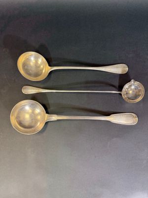 trois cuillères en argent sont alignées sur une table