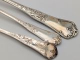 two silverware spoons and a fork on a white surface