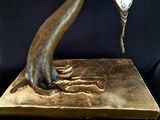 a bronze sculpture of a hand holding a spoon
