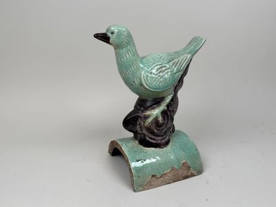 a small green bird sitting on top of a piece of wood