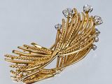 une image d'une broche en or et diamants sur une surface blanche