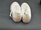 a pair of white sneakers that are on a black surface