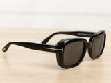 black sunglasses on a wooden table with a white wall in the background