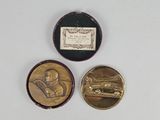 deux médailles d'or sur lesquelles figure l'image d'un homme dans une voiture