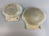 pair of white shell shaped bowls on stand on white surface
