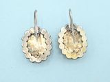 pair of silver and gold flower earrings on blue background