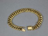 a close up of a gold bracelet on a white surface