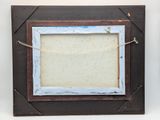 an old picture frame hanging on a wall with a string