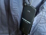a cell phone attached to the back of a man ' s jacket