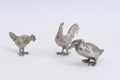 trois figurines d'oiseaux en argent sur un fond blanc