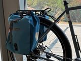 a bike parked in front of a window with a blue bag on it