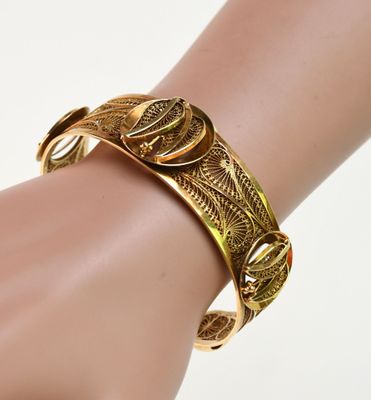 une image montrant un gros plan de la main d'une personne portant un bracelet en or