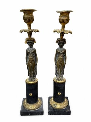 une paire de bougeoirs noirs et dorés ornés de figures