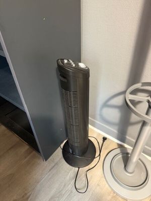a fan that is sitting on the floor next to a chair