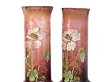 une paire de vases roses ornés de fleurs, posés sur une surface blanche