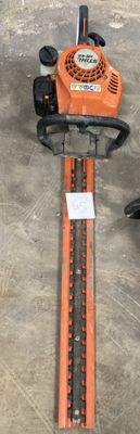 an orange and black chainsaw sitting on top of a floor next to a person