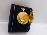 a small gold pocket watch on a velvet case