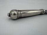 a silver object on a white surface with a black handle